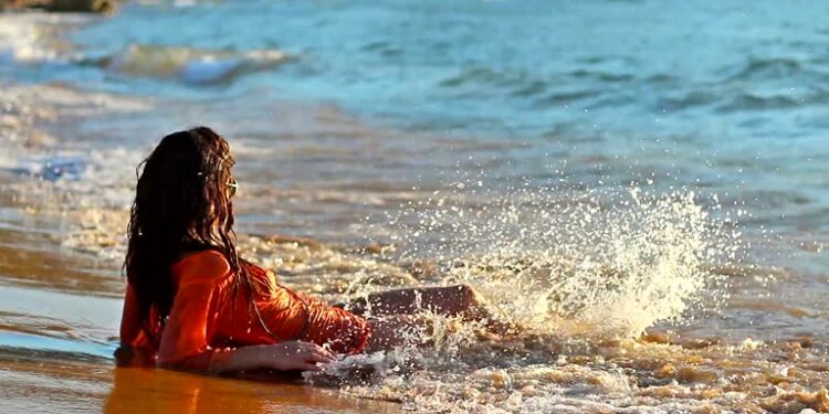 Girl lying on the beach and waves splash her body